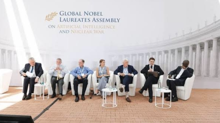 Seven people sitting in chairs on a stage